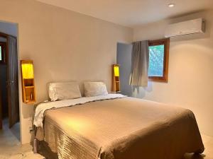 a bedroom with a bed with two lamps and a window at Pousada Colmeia - Praia de Santo André, Bahia in Santo André