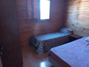 Habitación con 2 camas en una cabaña de madera en Cabaña a estrenar de 2 dormitorios a 3 km de playa, en Santa Vitória do Palmar