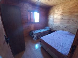 Habitación con 2 camas en una cabaña de madera en Cabaña a estrenar de 2 dormitorios a 3 km de playa, en Santa Vitória do Palmar