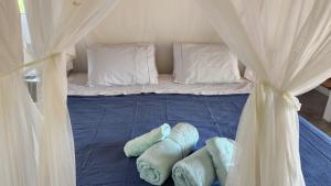 a bed with blue sheets and white pillows at Pousada Colmeia - Praia de Santo André, Bahia in Santo André