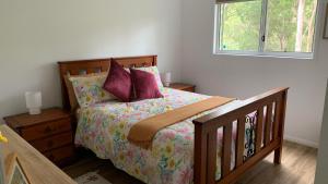 a bedroom with a bed with purple pillows and a window at Bush Beach Retreat in Caloundra