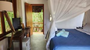 a bedroom with a bed and a tv and a window at Pousada Colmeia - Praia de Santo André, Bahia in Santo André