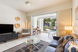 a living room with a couch and a tv at The Beach Club Premium Private Apartments in Palm Cove