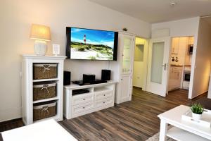 sala de estar con TV de pantalla plana en la pared en Strandhochhaus SC10 en Cuxhaven