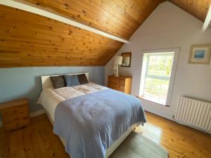 a bedroom with a large bed with a wooden ceiling at Maggie's Cottage in Thurles