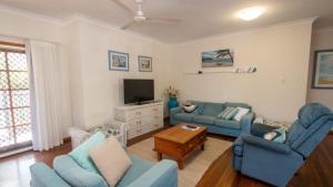 a living room with two blue couches and a tv at Picnic Cottage, Lovely Home Near The Beach in Picnic Bay