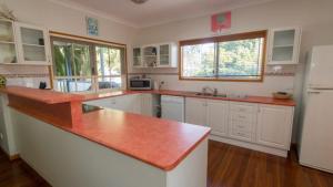 a kitchen with white cabinets and a red counter top at Picnic Cottage, Lovely Home Near The Beach in Picnic Bay