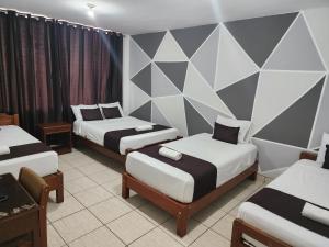 een kamer met drie bedden en een muur met driehoeken bij Hotel Villa del Sol in Piura