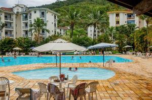 a pool at a resort with people swimming in it at Apartamento Wembley Tenis - Ubatuba 33 in Ubatuba