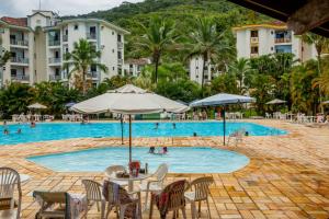 a pool at a resort with people in the water at Apartamento Wembley Tenis - Ubatuba 33 in Ubatuba