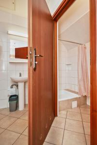 uma casa de banho com uma porta de madeira, um lavatório e uma banheira em Quadrans Hostel and Caffee na dworcu kolejowym Modlin 7 min jazdy lotniskowym autobusem wahadłowym em Nowy Dwór Mazowiecki