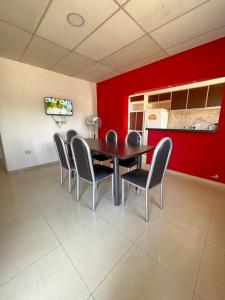 comedor con mesa, sillas y pared roja en salta 1019 Apart Firmat 5 en Firmat