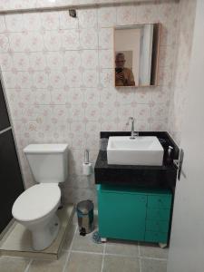 a man taking a picture of a bathroom with a toilet and sink at Apezinho da Soltony em Peruibe in Peruíbe