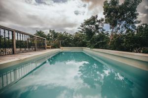 a pool of water with a fence and trees at Yum Kaax Boutique Villa in Tulum