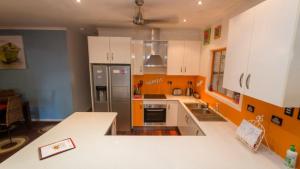 cocina con armarios de color naranja y blanco y nevera en Tamarinds Beach House en Arcadia