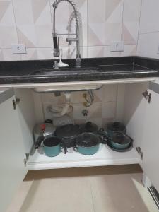 uma cozinha com panelas e frigideiras debaixo de um lavatório em Apto Alto Estilo Maranduba Ubatuba em Ubatuba