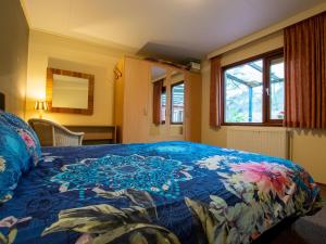 um quarto com uma cama com um cobertor azul com flores em Villa Maashorst em Uden