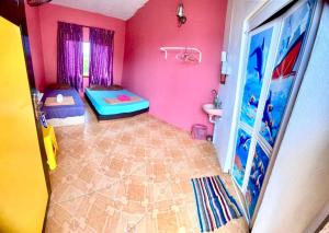 a room with two beds and a bathroom with pink walls at Rumah Hentian Ayah in Kuala Besut
