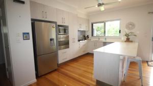 a kitchen with white cabinets and a stainless steel refrigerator at Le Belle Aimante, Magnetic Island in Horseshoe Bay