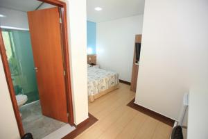a room with a bedroom with a bed and a open door at Hotel Oly Plaza in Piracicaba +28 photos