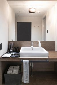 a bathroom with a white sink and a mirror at ALPHABED INN 小樽駅前 in Kita-hamachō