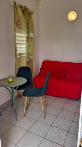 a living room with a red couch and a table and chairs at CHATAIGNE HEBERGEMENT in Petit-Bourg