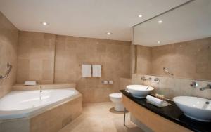 a bathroom with two sinks and a tub and a toilet at Holiday Inn Sydney Potts Point in Sydney