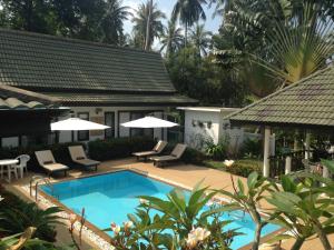 a swimming pool with chairs and a house at Baan Sawainam in Ko Tao
