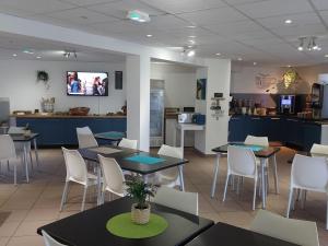 a restaurant with tables and chairs and a kitchen at Les Isles de Sola apartment in Grandcamp in Grandcamp-Maisy