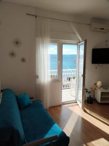 a living room with a blue couch and a balcony at Apartments by the sea Duce, Omis - 2731 in Dugi Rat
