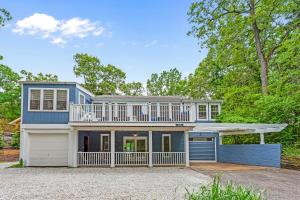 a large blue house with a balcony and a garage at Barefoot Cottage Pool House in Grand Beach