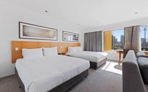 a hotel room with two beds and a couch at Holiday Inn Sydney Potts Point in Sydney