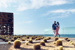 mężczyzna i kobieta spacerujący po plaży w obiekcie Zadún, a Ritz-Carlton Reserve w mieście San José del Cabo