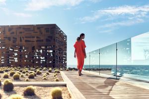 a woman in a red dress walking on a balcony of a building at Zadún, a Ritz-Carlton Reserve in San José del Cabo