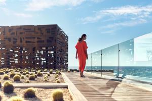 une femme en robe rouge marchant sur un balcon d'un bâtiment dans l'établissement Zadún, a Ritz-Carlton Reserve, à San José del Cabo