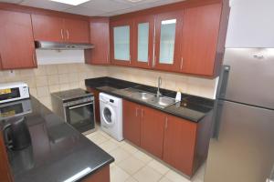 a kitchen with red cabinets and a sink and a refrigerator at The beach hostel Dubai in Dubai