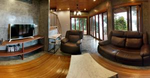 a living room with two leather chairs and a television at Cashewnut Cove in Ko Lipe