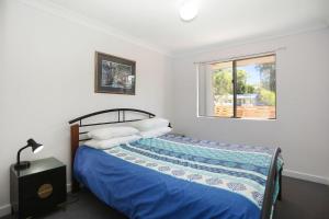 a bedroom with a bed with blue sheets and a window at Resort Style Holiday in Hawks Nest