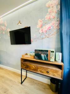 a tv on a wall with a painting of flowers at New studio flat overlooking city centre in Kingston upon Thames