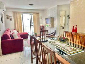 a living room with a table and a red couch at Apto espaçoso uma quadra do mar com garagem in Balneário Camboriú +12 photos