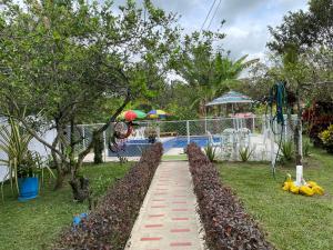 a walkway leading to a pool with fruits on the grass at Casa Campestre El Encanto in Trujillo