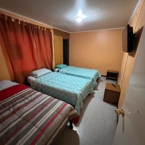 um quarto com duas camas e uma televisão em HOSPEDAJE DA VINCI PARA TURISTAS y PERSONAL LABORAL em Calama