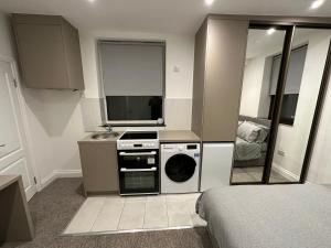 a small kitchen with a washing machine and a sink at Unique Modern, 1 Bed Flat, 15 Mins To Central London in Hendon