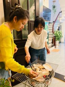 Dos mujeres están cocinando comida en una parrilla en GIA THÀNH HOMESTAY, en Hoi An