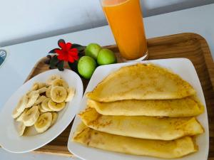 un vassoio di legno con pancake, banane e un piatto di frutta di GIA THÀNH HOMESTAY a Hoi An