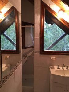 baño con lavabo, ducha y ventana en Casa Carilo en Cariló