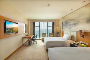 um quarto de hotel com duas camas e uma secretária em Holiday Inn Guangzhou Science City, an IHG Hotel em Guangzhou