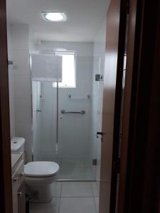 a bathroom with a toilet and a glass shower at Apartamento residencial in Blumenau