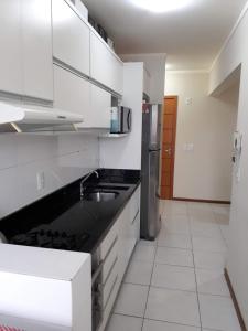 a kitchen with white cabinets and a black counter top at Apartamento residencial in Blumenau