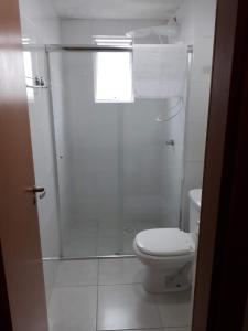 a white bathroom with a shower and a toilet at Apartamento residencial in Blumenau